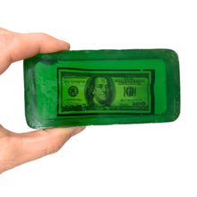 Load image into Gallery viewer, Green bar of soap with a printed dollar bill design held by a hand on a white background